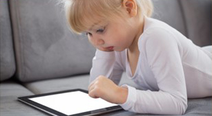 toddler using a tablet on the couch