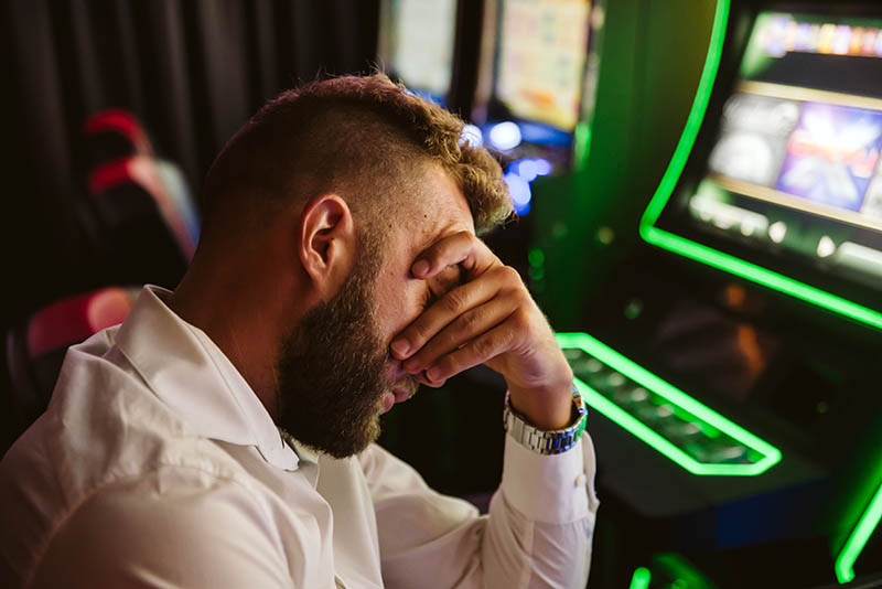 stressed-male-gambling-at-slot-machine