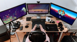 teen playing a video game on multiple computer monitors