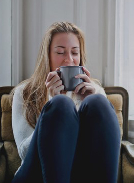 relaxed person sipping a warm drink out of a mug