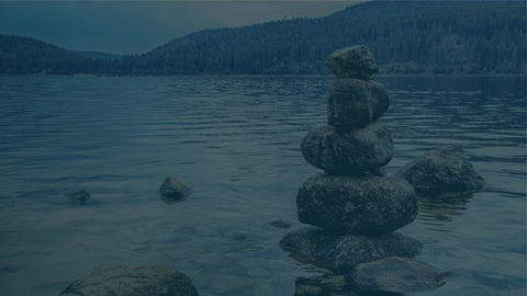 stack of rocks sitting on the edge of a peaceful lake
