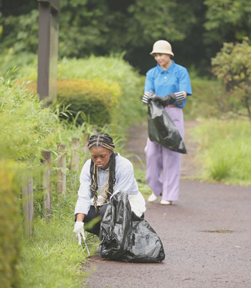 Two teenagers picking up litter on a walking trail.